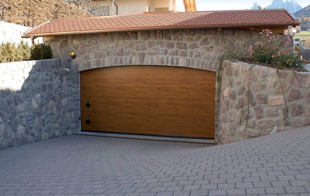 Portone sezionale effetto legno per garage con arco in pietra, provincia di Vicenza