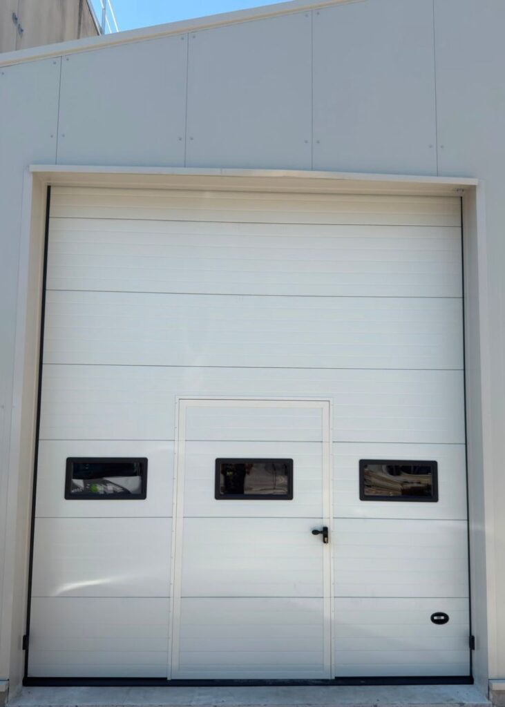 Portone sezionale industriale con porta pedonale integrata